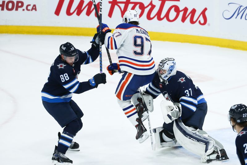 Nov 30, 2023; Winnipeg, Manitoba, CAN; Edmonton Oilers forward Connor McDavid (97) tries to screen Winnipeg Jets goalie Connor Hellebuyck (37) during the third period at Canada Life Centre. Mandatory Credit: Terrence Lee-USA TODAY Sports