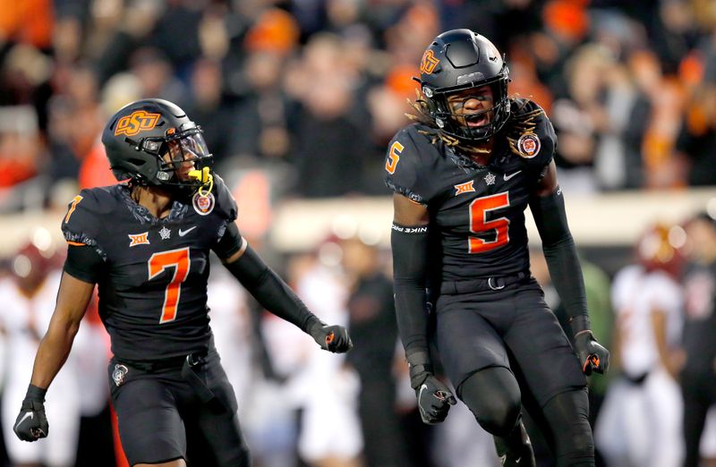 Nov 12, 2022; Stillwater, Oklahoma, USA;  Oklahoma State Cowboys safety Kendal Daniels (5) and cornerback Jabbar Muhammad (7) celebrate after a defensive stop against the Iowa State Cyclones in the fourth quarter at Boone Pickens Stadium. OSU won 20-14. Mandatory Credit: Sarah Phipps-USA TODAY Sports