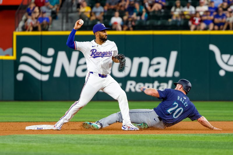 Sep 21, 2024; Arlington, Texas, USA; Texas Rangers second base Marcus Semien (2) turns a double play with Seattle Mariners outfielder Luke Raley (20) sliding into second base during the fifth inning at Globe Life Field. Mandatory Credit: Andrew Dieb-Imagn Images