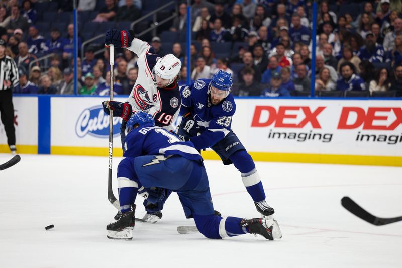 Mar 4, 2025; Tampa, Florida, USA; Columbus Blue Jackets center Adam Fantilli (19) and Tampa Bay Lightning center Zemgus Girgensons (28) battle for the puck in the third period at Amalie Arena. Mandatory Credit: Nathan Ray Seebeck-Imagn Images