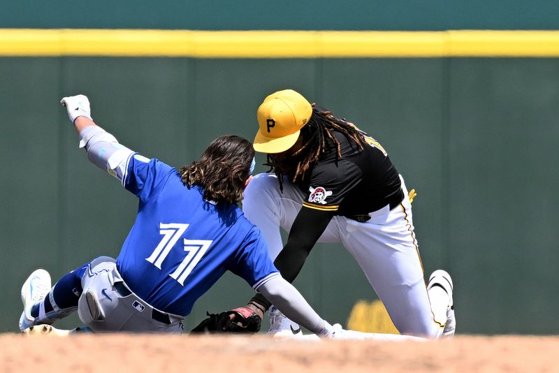 Mar 25, 2024; Bradenton, Florida, USA; Pittsburgh Pirates shortstop Oniel Cruz (15) attempts to tag out Toronto Blue Jays shortstop Bo Bichette (11) in the third inning of the spring training game  at LECOM Park. Mandatory Credit: Jonathan Dyer-USA TODAY Sports