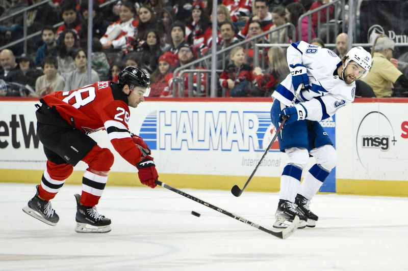 Feb 25, 2024; Newark, New Jersey, USA; Tampa Bay Lightning left wing Brandon Hagel (38) passes the puck while being defended by New Jersey Devils right wing Timo Meier (28) during the first period at Prudential Center. Mandatory Credit: John Jones-USA TODAY Sports