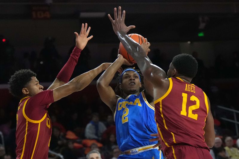 Jan 27, 2025; Los Angeles, California, USA; UCLA Bruins guard Dylan Andrews (2) shoots the ball against Southern California Trojans guard Kevin Patton Jr. (8) and forward Rashaun Agee (12) in the first half at Galen Center. Mandatory Credit: Kirby Lee-Imagn Images