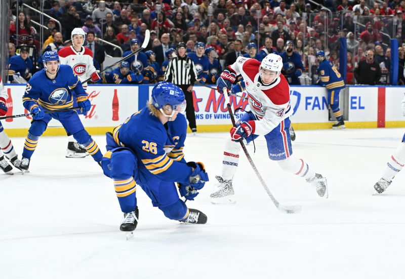 Nov 11, 2024; Buffalo, New York, USA; Montreal Canadiens defenseman Lane Hutson (48) shoots the puck with Buffalo Sabres defenseman Rasmus Dahlin (26) defending in the third period at KeyBank Center. Mandatory Credit: Mark Konezny-Imagn Images