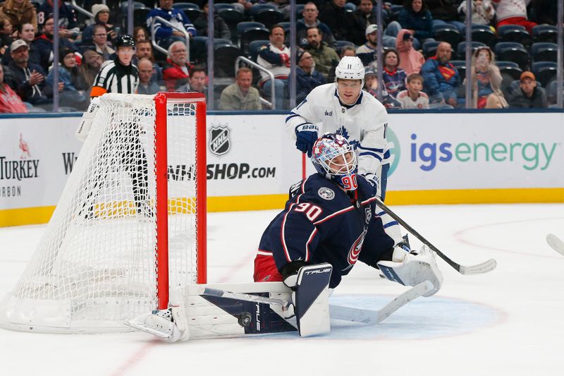 Oct 29, 2025; Columbus, Ohio, USA; Columbus Blue Jackets goalie Elvis Merzlikins (90) makes a pad save as Toronto Maple Leafs center Max Domi (11) looks for a rebound during the third period at Nationwide Arena. Mandatory Credit: Russell LaBounty-Imagn Images