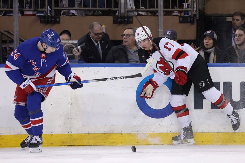 Mar 11, 2024; New York, New York, USA; New York Rangers right wing Kaapo Kakko (24) and New Jersey Devils defenseman Simon Nemec (17) fight for the puck during the first period at Madison Square Garden. Mandatory Credit: Brad Penner-USA TODAY Sports