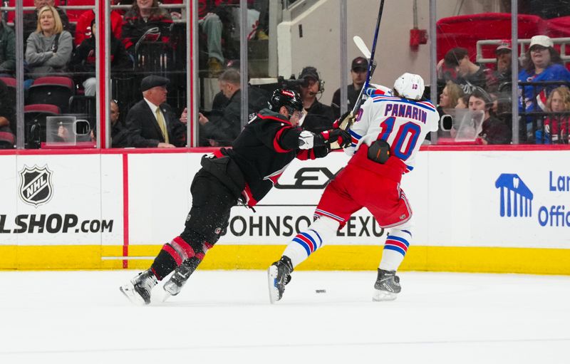 Apr 12, 2025; Raleigh, North Carolina, USA;  New York Rangers left wing Artemi Panarin (10) is checks by Carolina Hurricanes defenseman Dmitry Orlov (7) during the first period at Lenovo Center. Mandatory Credit: James Guillory-Imagn Images