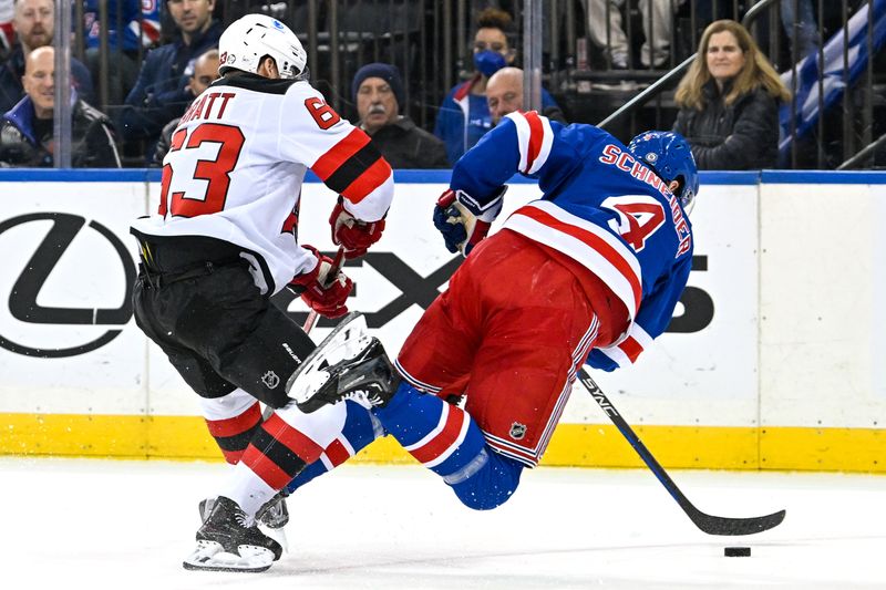 Dec 2, 2024; New York, New York, USA;  New Jersey Devils left wing Jesper Bratt (63) checks New York Rangers defenseman Braden Schneider (4) during the first period at Madison Square Garden. Mandatory Credit: Dennis Schneidler-Imagn Images