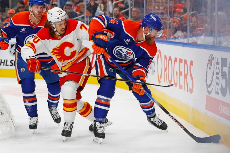 Oct 13, 2024; Edmonton, Alberta, CAN; Edmonton Oilers defensemen Mattias Ekholm (14) and Calgary Flames forward Ryan Lomberg (70) battle along the boards for a loose puck  during the second period at Rogers Place. Mandatory Credit: Perry Nelson-Imagn Images