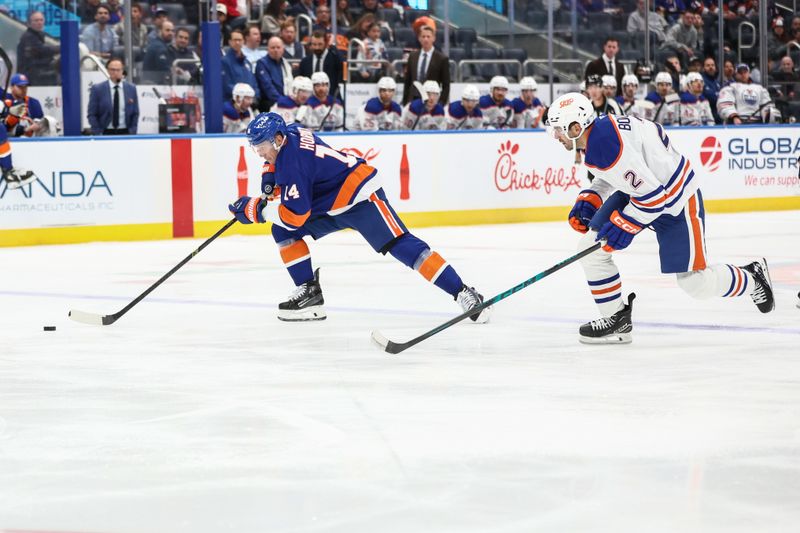 Oct 16, 2025; Elmont, New York, USA; New York Islanders center Bo Horvat (14) and Edmonton Oilers defenseman Evan Bouchard (2) chase the puck in the second period at UBS Arena. Mandatory Credit: Wendell Cruz-Imagn Images