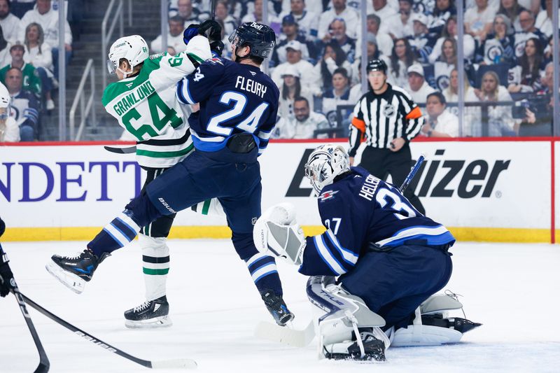 May 7, 2025; Winnipeg, Manitoba, CAN; Winnipeg Jets defenseman Hayden Fleury (24) jostles for position with Dallas Stars forward Mikael Granlund (64) during the first period in game one of the second round of the 2025 Stanley Cup Playoffs at Canada Life Centre. Mandatory Credit: Terrence Lee-Imagn Images