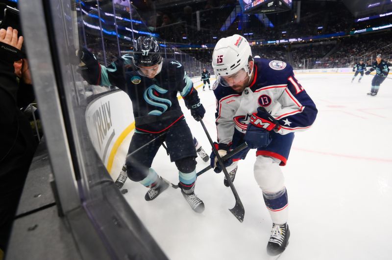 Nov 12, 2024; Seattle, Washington, USA; Seattle Kraken center Yanni Gourde (37) and Columbus Blue Jackets defenseman Dante Fabbro (15) play the puck during the third period at Climate Pledge Arena. Mandatory Credit: Steven Bisig-Imagn Images