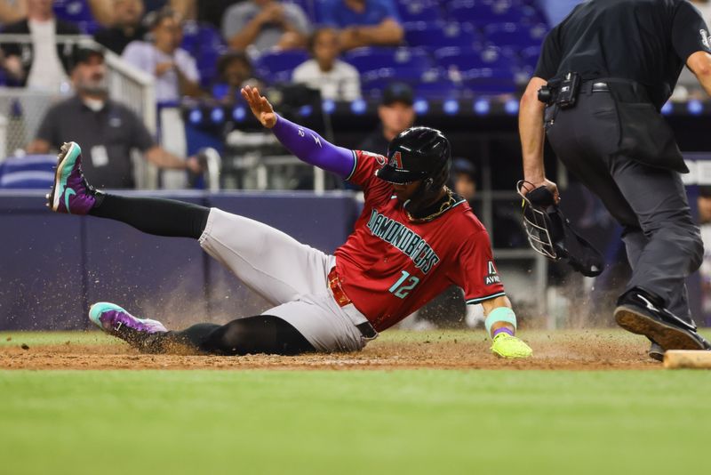 Aug 19, 2024; Miami, Florida, USA; Arizona Diamondbacks left fielder Lourdes Gurriel Jr. (12) slides at home plate and scores after an RBI single by catcher Adrian Del Castillo (not pictured) against the Miami Marlins during the seventh inning at loanDepot Park. Mandatory Credit: Sam Navarro-USA TODAY Sports