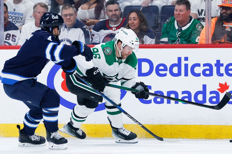 May 7, 2025; Winnipeg, Manitoba, CAN; Dallas Stars forward Mikko Rantanen (96) tries to skate away from Winnipeg Jets defenseman Neal Pionk (4) during the first period in game one of the second round of the 2025 Stanley Cup Playoffs at Canada Life Centre. Mandatory Credit: Terrence Lee-Imagn Images