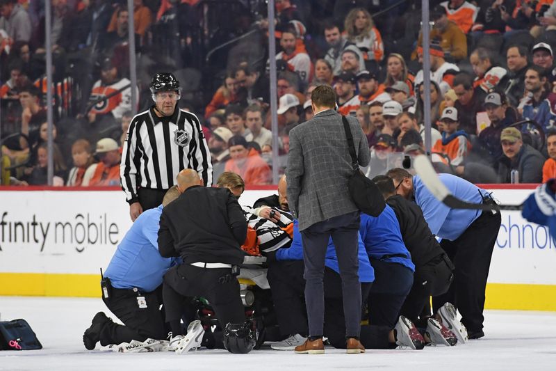 Nov 18, 2024; Philadelphia, Pennsylvania, USA; Referee Barry Anderson (20) is carted off the ice after colliding with a player during game between Philadelphia Flyers and Colorado Avalanche in the first period at Wells Fargo Center. Mandatory Credit: Eric Hartline-Imagn Images