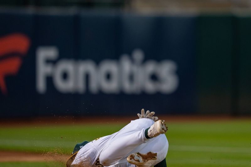 Aug 5, 2024; Oakland, California, USA;  Oakland Athletics shortstop Max Schuemann (12) after the catch falls over on the warmup pitching mound in foul territory against the Chicago White Sox during the sixth inning at Oakland-Alameda County Coliseum. Mandatory Credit: Neville E. Guard-USA TODAY Sports