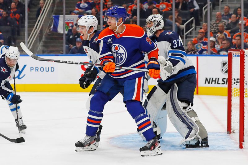 Oct 9, 2024; Edmonton, Alberta, CAN; Edmonton Oilers forward Corey Perry (90) battles with Winnipeg Jets defensemen Hayden Fleury (24) in front of goaltender Connor Hellebuyck (37) during the third period at Rogers Place. Mandatory Credit: Perry Nelson-Imagn Images