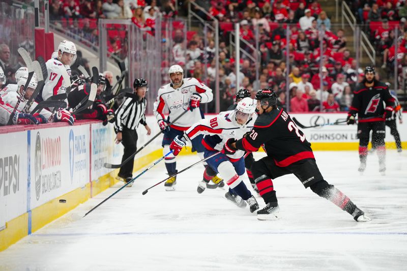 Nov 3, 2024; Raleigh, North Carolina, USA;  Carolina Hurricanes center Sebastian Aho (20) and Washington Capitals left wing Pierre-Luc Dubois (80) chase after the puck during the third period at Lenovo Center. Mandatory Credit: James Guillory-Imagn Images