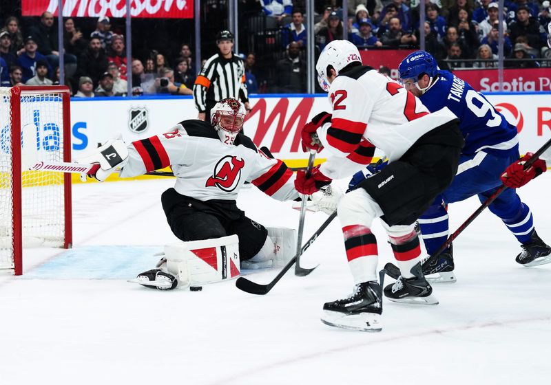 Dec 30, 2025; Toronto, Ontario, CAN; Toronto Maple Leafs center John Tavares (91) battles with New Jersey Devils defenseman Brett Pesce (22) in front of goaltender Jacob Markstrom (25) during the first period at Scotiabank Arena. Mandatory Credit: Nick Turchiaro-Imagn Images