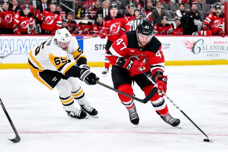 Nov 8, 2025; Newark, New Jersey, USA; New Jersey Devils left wing Paul Cotter (47) skates with the puck while defended by Pittsburgh Penguins defenseman Erik Karlsson (65) during the second period at Prudential Center. Mandatory Credit: John Jones-Imagn Images