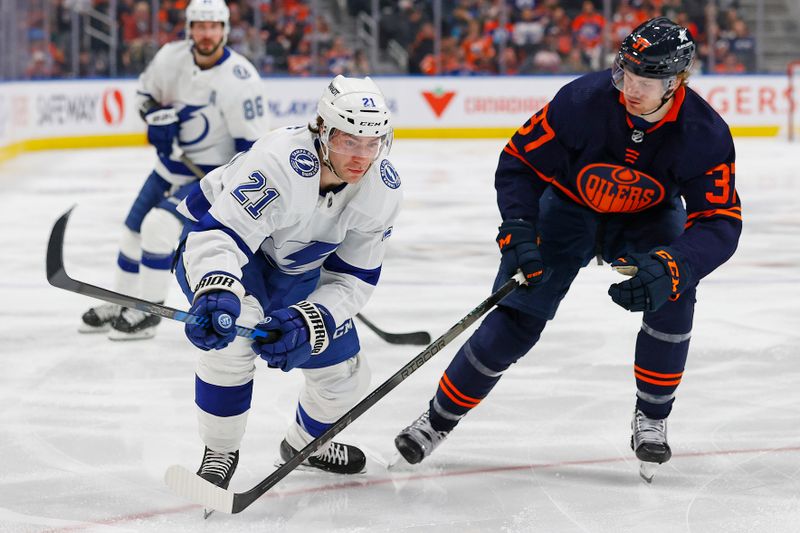 Dec 14, 2023; Edmonton, Alberta, CAN; Tampa Bay Lightning forward Brayden Point (21)  and Edmonton Oilers forward Warren Foegele (37) look for a loose puck during the second period at Rogers Place. Mandatory Credit: Perry Nelson-USA TODAY Sports