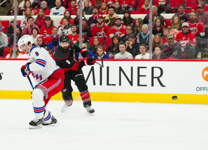 Nov 27, 2024; Raleigh, North Carolina, USA;  Carolina Hurricanes defenseman Brent Burns (8) gets the shot away against New York Rangers defenseman Jacob Trouba (8) during the first period at Lenovo Center. Mandatory Credit: James Guillory-Imagn Images