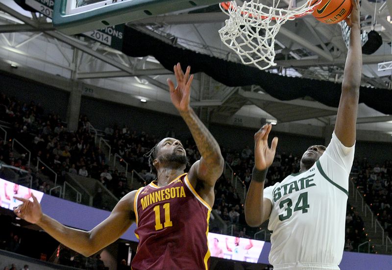 Jan 28, 2025; East Lansing, Michigan, USA;  Michigan State Spartans forward Xavier Booker (34) scores past Minnesota Golden Gophers guard Femi Odukale (11) during the second half at Jack Breslin Student Events Center. Mandatory Credit: Dale Young-Imagn Images