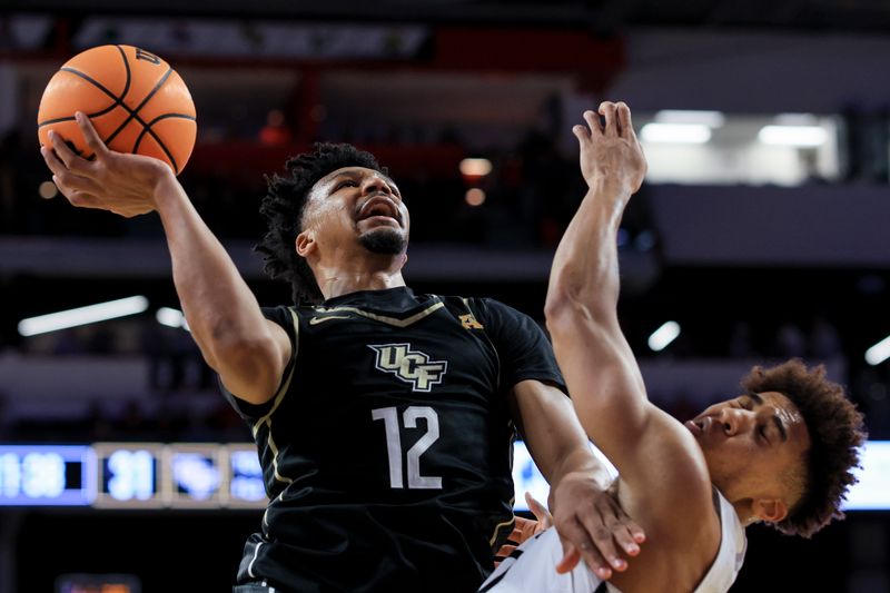 Feb 4, 2023; Cincinnati, Ohio, USA;  UCF Knights guard Ithiel Horton (12) drives to the basket as he fouls Cincinnati Bearcats guard Rob Phinisee (10) in the second half at Fifth Third Arena. Mandatory Credit: Aaron Doster-USA TODAY Sports