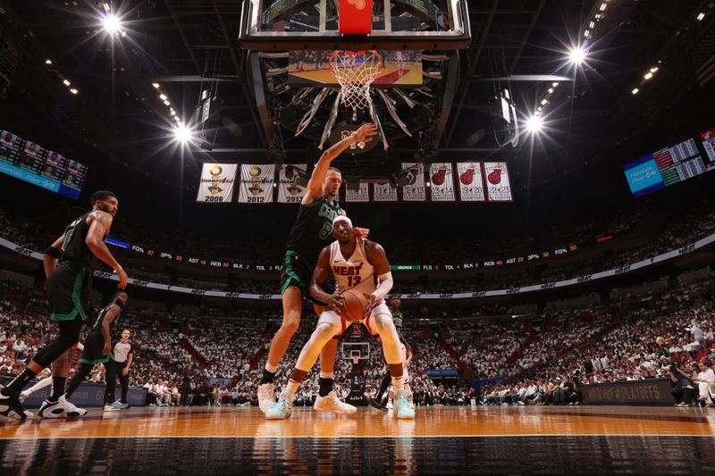 MIAMI, FL - APRIL 27: Bam Adebayo #13 of the Miami Heat drives to the basket against Kristaps Porzingis #8 of the Boston Celtics during the game during Round 1 Game 3 of the 2024 NBA Playoffs on April 27, 2024 at Kaseya Center in Miami, Florida. NOTE TO USER: User expressly acknowledges and agrees that, by downloading and or using this Photograph, user is consenting to the terms and conditions of the Getty Images License Agreement. Mandatory Copyright Notice: Copyright 2024 NBAE (Photo by Issac Baldizon/NBAE via Getty Images)