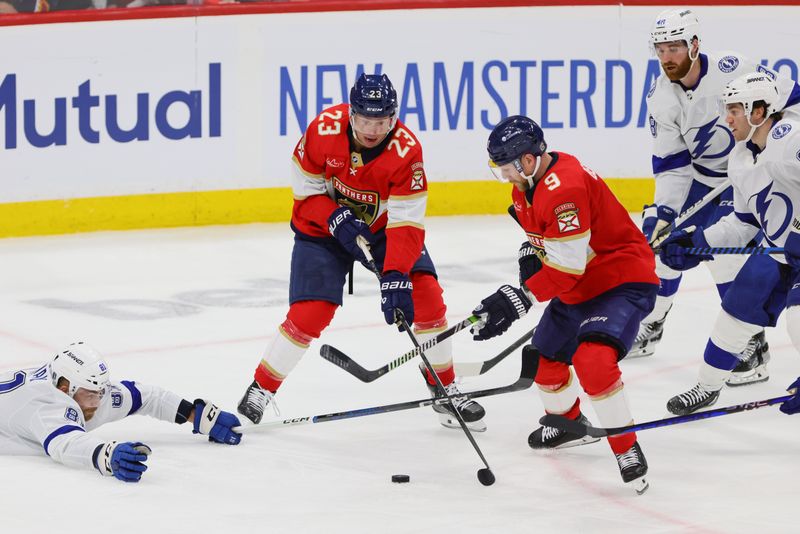 Apr 21, 2024; Sunrise, Florida, USA; Florida Panthers center Carter Verhaeghe (23) and Florida Panthers center Sam Bennett (9) battle for the puck against Tampa Bay Lightning defenseman Erik Cernak (81) during the third period in game one of the first round of the 2024 Stanley Cup Playoffs at Amerant Bank Arena. Mandatory Credit: Sam Navarro-USA TODAY Sports