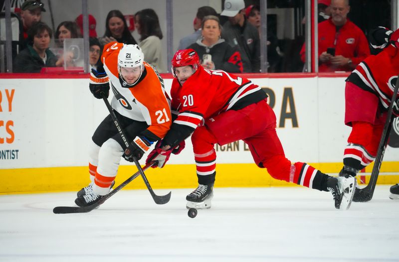 Mar 21, 2024; Raleigh, North Carolina, USA; Carolina Hurricanes center Sebastian Aho (20) and Philadelphia Flyers center Scott Laughton (21) battle over the puck during the second period at PNC Arena. Mandatory Credit: James Guillory-USA TODAY Sports