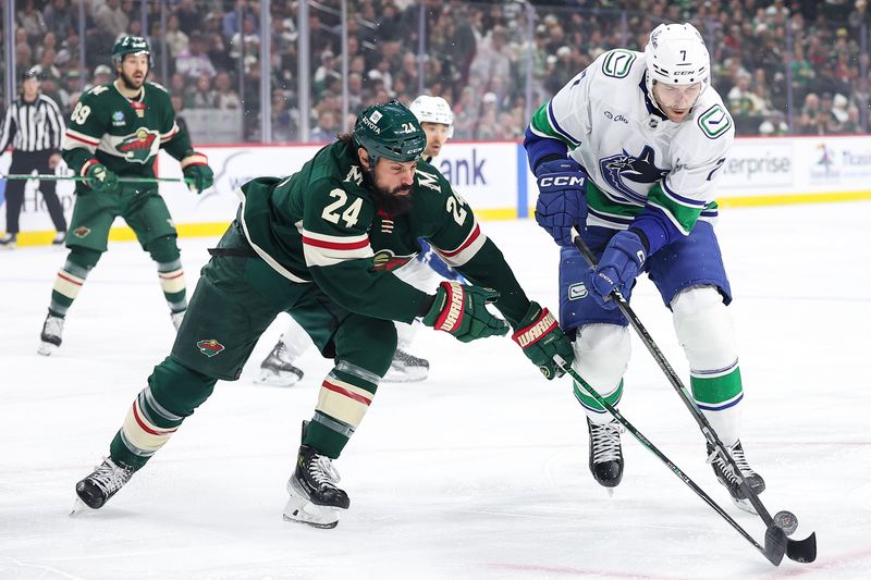 Dec 3, 2024; Saint Paul, Minnesota, USA; Vancouver Canucks defenseman Carson Soucy (7) and Minnesota Wild defenseman Zach Bogosian (24) compete for the puck during the first period at Xcel Energy Center. Mandatory Credit: Matt Krohn-Imagn Images