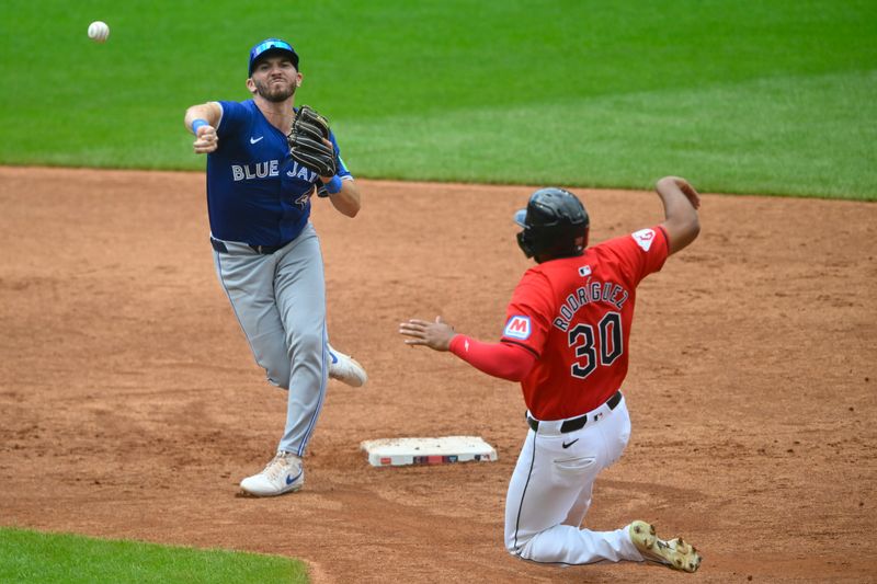 Jun 23, 2024; Cleveland, Ohio, USA; Toronto Blue Jays second baseman Spencer Horwitz (48) turns a double play beside Cleveland Guardians right fielder Johnathan Rodriguez (30) in the third inning at Progressive Field. Mandatory Credit: David Richard-USA TODAY Sports