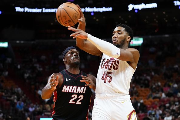 MIAMI, FLORIDA - DECEMBER 08: Donovan Mitchell #45 of the Cleveland Cavaliers throws a pass over Jimmy Butler #22 of the Miami Heat during the first quarter at Kaseya Center on December 08, 2023 in Miami, Florida. NOTE TO USER: User expressly acknowledges and agrees that, by downloading and or using this photograph, User is consenting to the terms and condtions of the Getty Images License Agreement.  (Photo by Rich Storry/Getty Images)