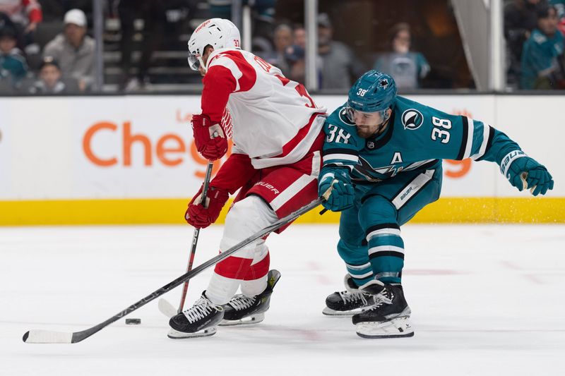 Jan 2, 2024; San Jose, California, USA; San Jose Sharks defenseman Mario Ferraro (38) attempts to reach for the puck during the third period against Detroit Red Wings left wing J.T. Compher (37) at SAP Center at San Jose. Mandatory Credit: Stan Szeto-USA TODAY Sports