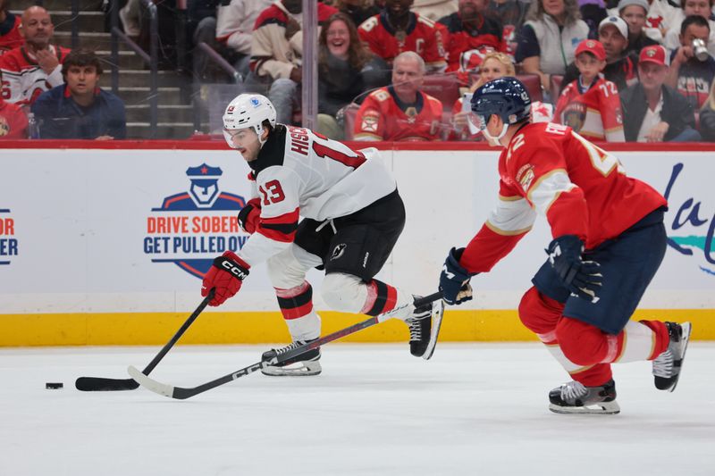 Nov 20, 2025; Sunrise, Florida, USA; New Jersey Devils center Nico Hischier (13) moves the puck against Florida Panthers defenseman Gustav Forsling (42) during the third period at Amerant Bank Arena. Mandatory Credit: Sam Navarro-Imagn Images