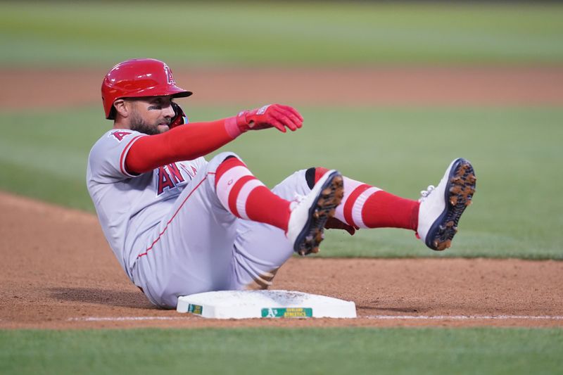 Jul 19, 2024; Oakland, California, USA; Los Angeles Angels center fielder Kevin Pillar (12) sits on the dirt after advancing to third base on a wild pitch against the Oakland Athletics in the sixth inning at Oakland-Alameda County Coliseum. Mandatory Credit: Cary Edmondson-USA TODAY Sports