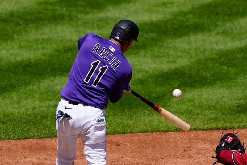 Aug 17, 2025; Denver, Colorado, USA; Colorado Rockies shortstop Orlando Arcia (11) RBI singles in the fifth inning against the Arizona Diamondbacks at Coors Field. Mandatory Credit: Ron Chenoy-Imagn Images