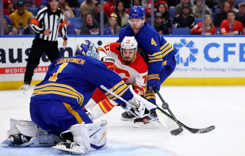 Nov 9, 2024; Buffalo, New York, USA;  Buffalo Sabres goaltender Ukko-Pekka Luukkonen (1) makes a save on Calgary Flames left wing Ryan Lomberg (70) as Buffalo Sabres defenseman Bowen Byram (4) defends during the third period at KeyBank Center. Mandatory Credit: Timothy T. Ludwig-Imagn Images