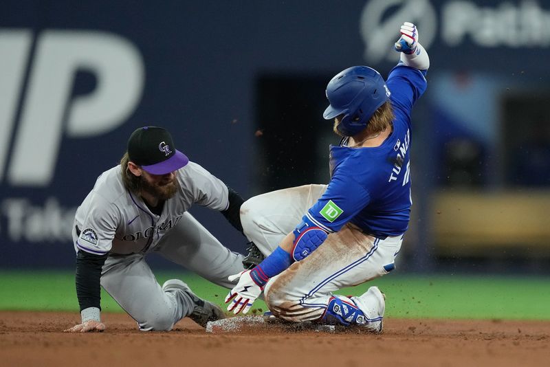 Apr 14, 2024; Toronto, Ontario, CAN; Toronto Blue Jays designated hitter Justin Turner (2) slides into second base against Colorado Rockies second baseman Brendan Rodgers (7) on his one run double during the third inning at Rogers Centre. Mandatory Credit: John E. Sokolowski-USA TODAY Sports