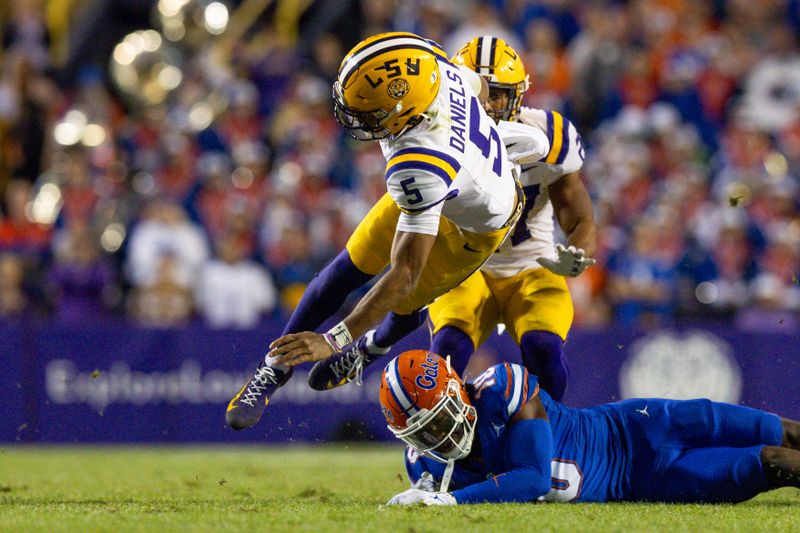 Nov 11, 2023; Baton Rouge, Louisiana, USA;  LSU Tigers quarterback Jayden Daniels (5) is tackled by Florida Gators safety Miguel Mitchell (10) during the second half at Tiger Stadium. Mandatory Credit: Stephen Lew-USA TODAY Sports