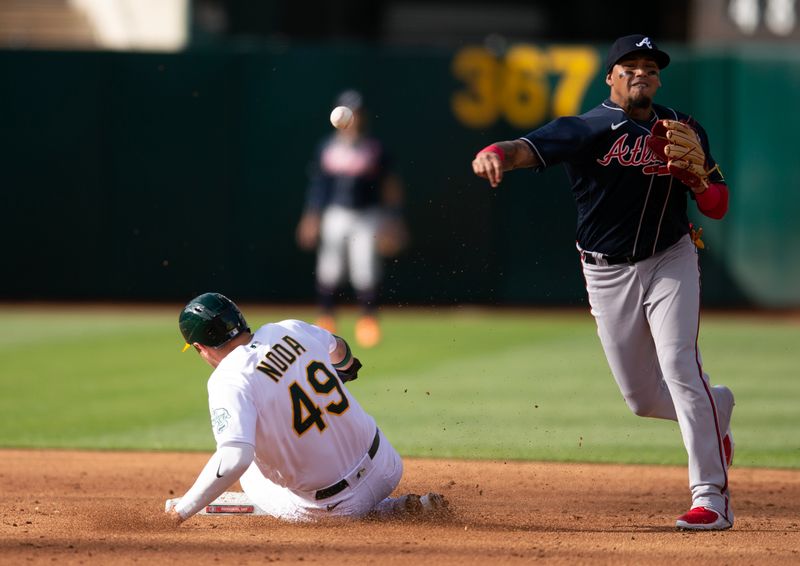 May 29, 2023; Oakland, California, USA; Atlanta Braves shortstop Orlando Arcia (11) throws over Oakland Athletics first baseman Ryan Noda (49) to complete a double play during the third inning at Oakland-Alameda County Coliseum. Mandatory Credit: D. Ross Cameron-USA TODAY Sports