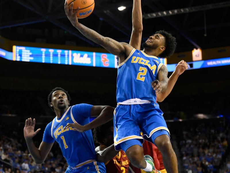 Feb 24, 2026; Los Angeles, California, USA; UCLA Bruins guard Donovan Dent (2) scores past Southern California Trojans forwards Jacob Cofie (6) and  Ezra Ausar (2) during the second half tat Pauley Pavilion presented by Wescom Financial. Mandatory Credit: Robert Hanashiro-Imagn Images