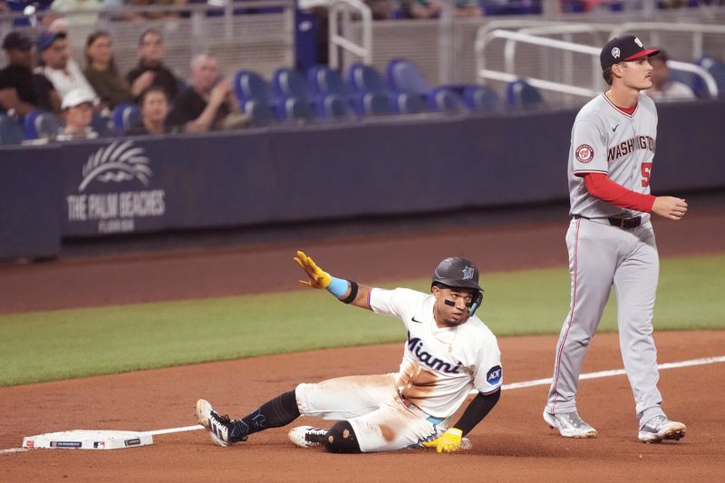 Sep 11, 2025; Miami, Florida, USA;  Miami Marlins shortstop Maximo Acosta (24) takes third base after an errant throw let him steal second base in the fourth inning as Washington Nationals third baseman Brady House (55) looks on at loanDepot Park. Mandatory Credit: Jim Rassol-Imagn Images