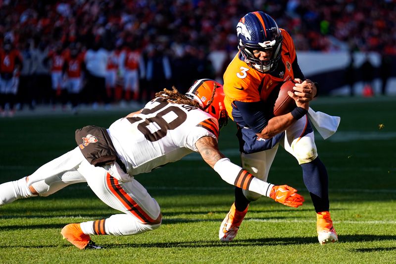 Denver Broncos quarterback Russell Wilson (3) scores past Cleveland Browns cornerback Mike Ford (28) during the first half of an NFL football game on Sunday, Nov. 26, 2023, in Denver. (AP Photo/Jack Dempsey)