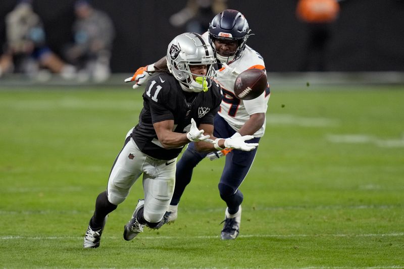 Las Vegas Raiders wide receiver Tre Tucker (11) makes a catch as Denver Broncos cornerback Ja'Quan McMillian defends during the second half of an NFL football game, Sunday, Nov. 24, 2024, in Las Vegas. (AP Photo/John Locher)