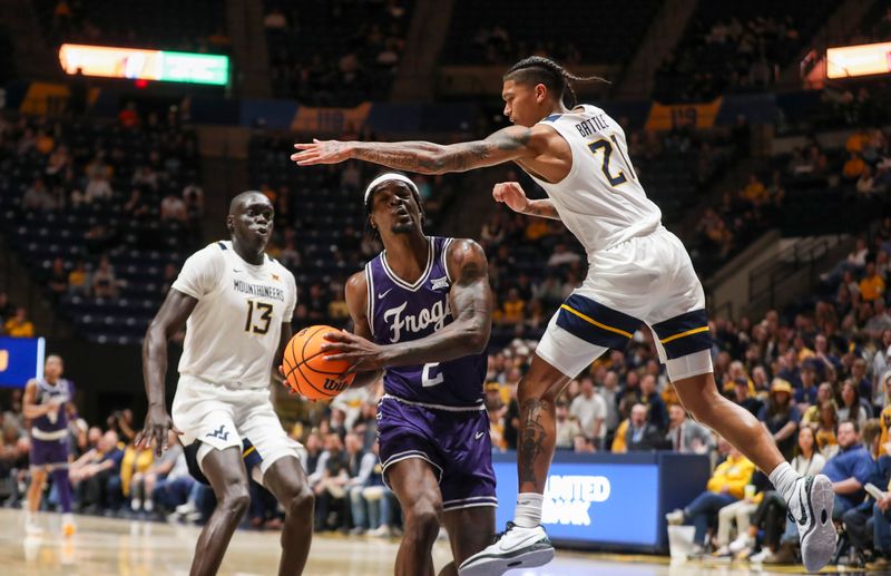 Mar 6, 2024; Morgantown, West Virginia, USA; TCU Horned Frogs forward Emanuel Miller (2) makes a move in the lane while defended by West Virginia Mountaineers guard RaeQuan Battle (21) during the first half at WVU Coliseum. Mandatory Credit: Ben Queen-USA TODAY Sports