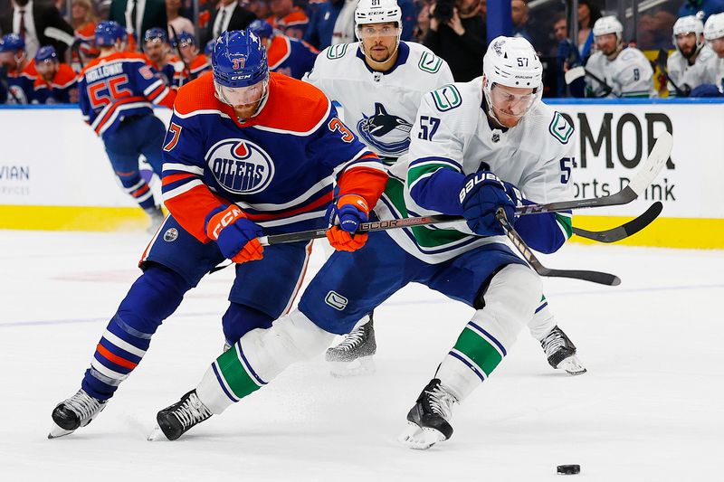 May 18, 2024; Edmonton, Alberta, CAN; Edmonton Oilers forward Warren Foegele (37) and Vancouver Canucks defensemen Tyler Myers (57) chase a loose puck during the third period in game six of the second round of the 2024 Stanley Cup Playoffs at Rogers Place. Mandatory Credit: Perry Nelson-USA TODAY Sports