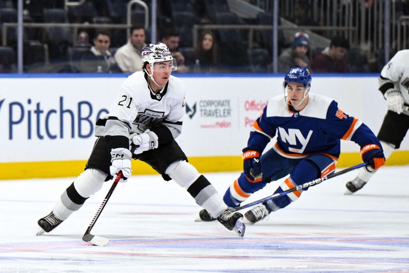 Dec 9, 2023; Elmont, New York, USA; Los Angeles Kings defenseman Jordan Spence (21) skates with the puck while being defended by New York Islanders center Jean-Gabriel Pageau (44) during the first period at UBS Arena. Mandatory Credit: John Jones-USA TODAY Sports