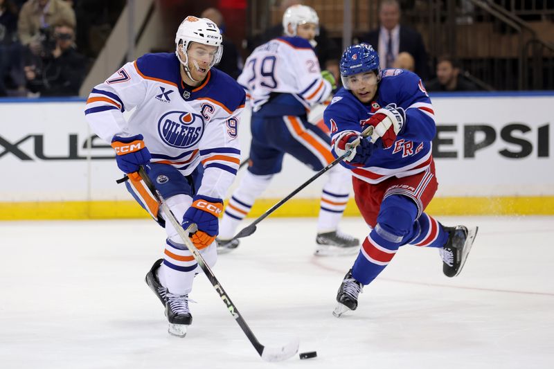 Oct 14, 2025; New York, New York, USA; Edmonton Oilers center Connor McDavid (97) fights for the puck against New York Rangers defenseman Braden Schneider (4) during the second period at Madison Square Garden. Mandatory Credit: Brad Penner-Imagn Images